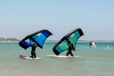 two beginner wingfoiling students are learning wing control on big SUP boards