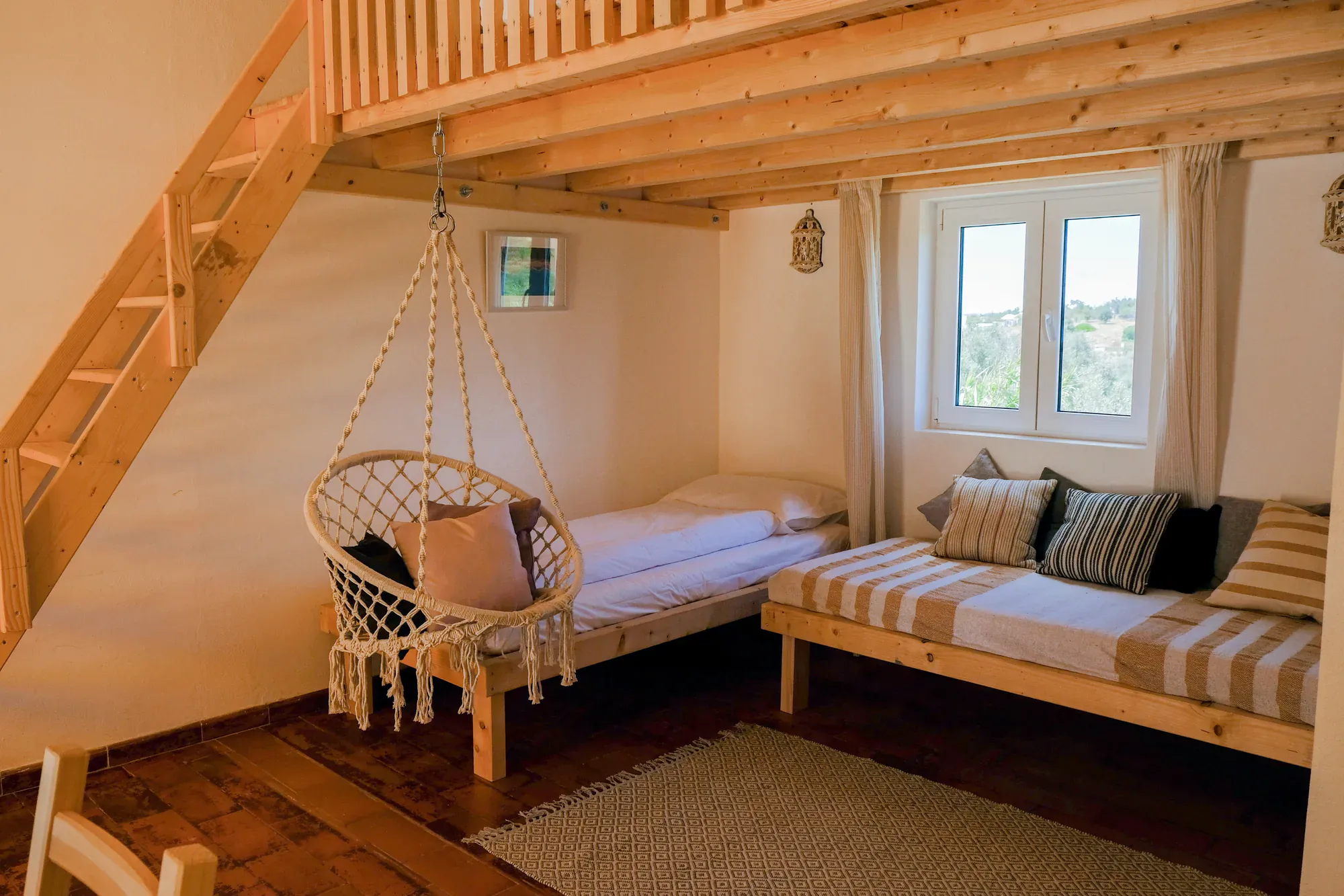 Bungalow interior with mezzanine loft, hammock chair and beds at Algarve Watersport surf camp