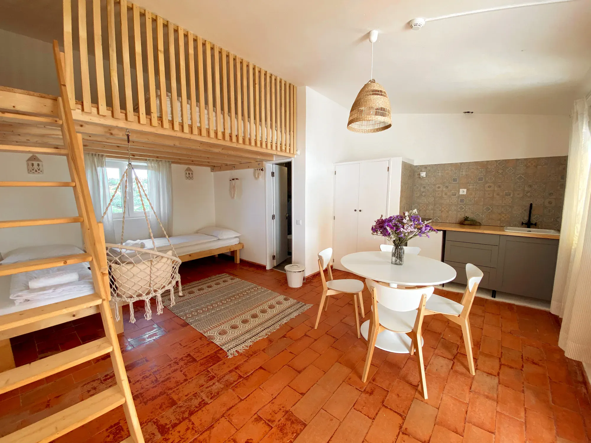 Bungalow interior with mezzanine loft, kitchenette and dining area at Algarve Watersport surf camp