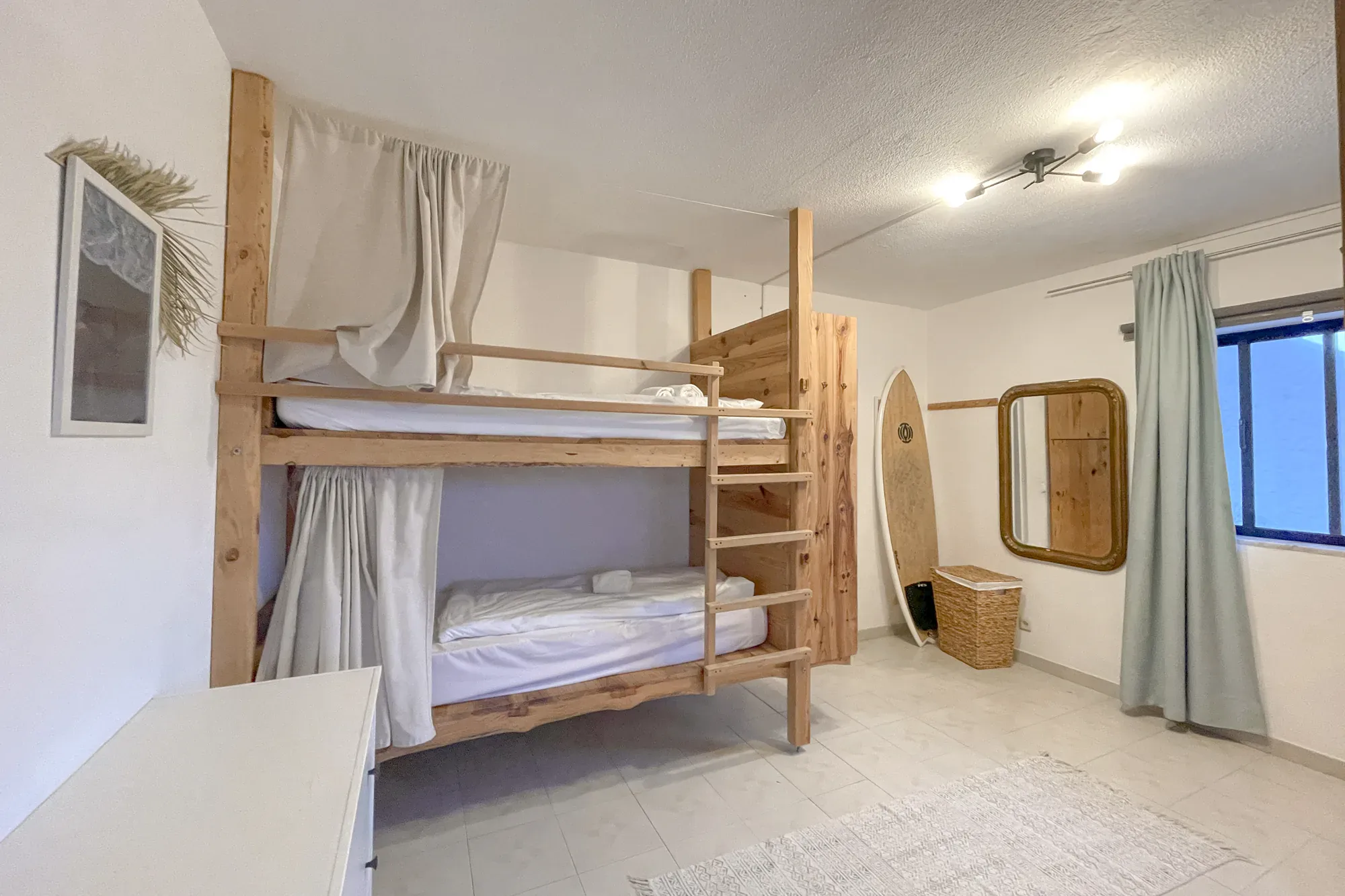 Dorm room with bunk bed, surfboard decor and curtains at Algarve Watersport