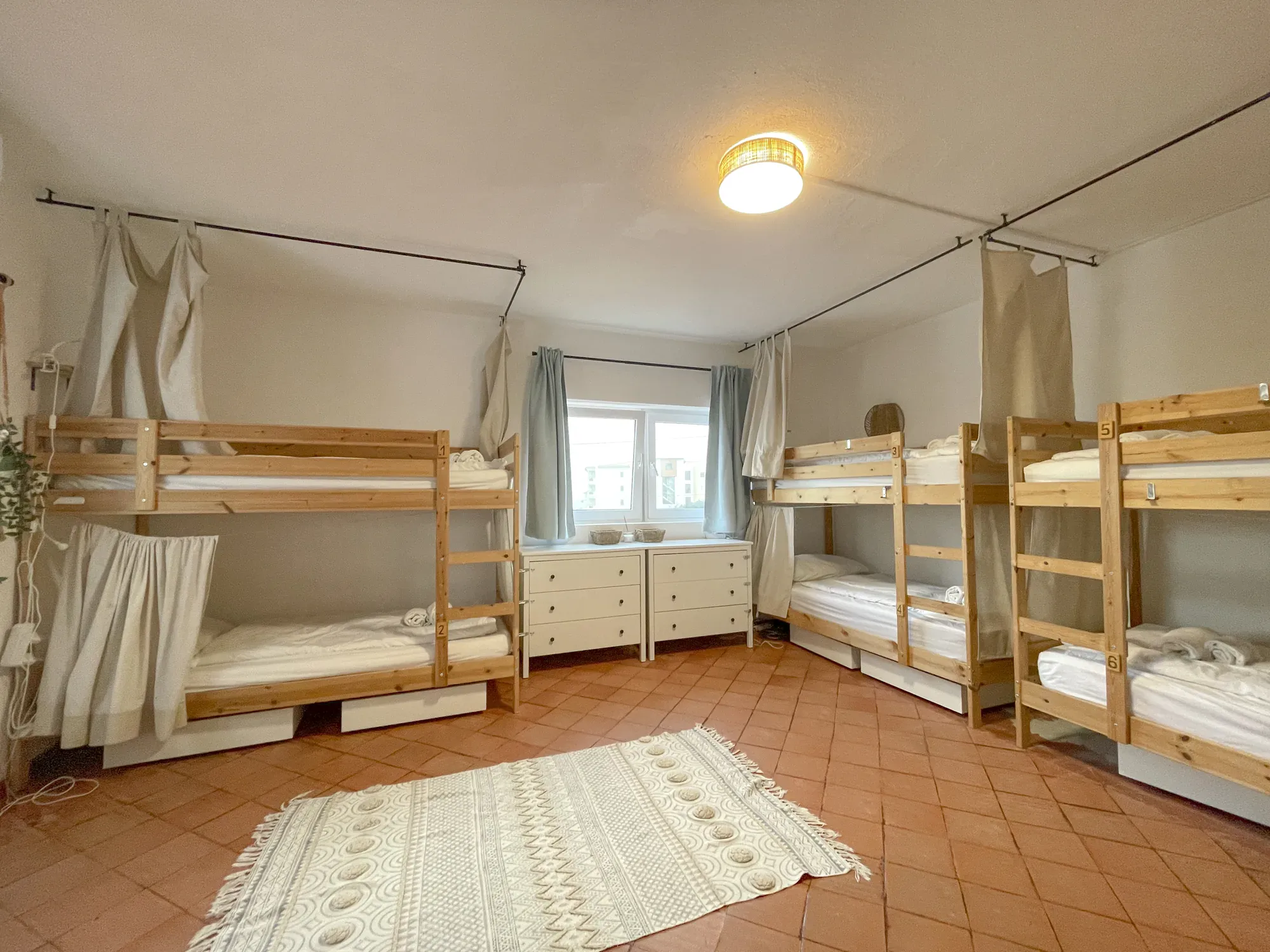 Shared dorm room with four bunk beds and privacy curtains at Algarve Watersport surf camp