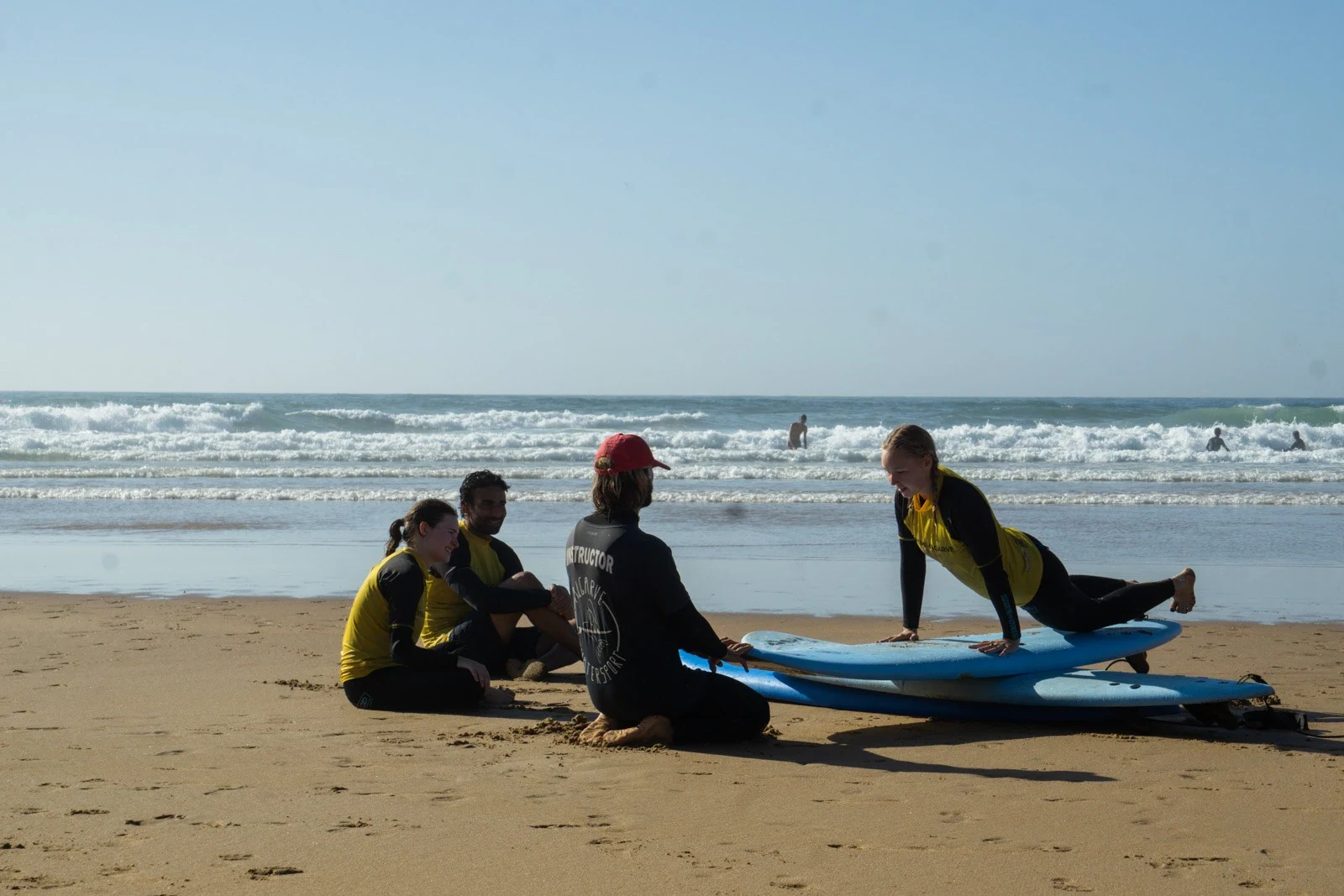 Surf instructor leading a warmup stretch with students on the beach
