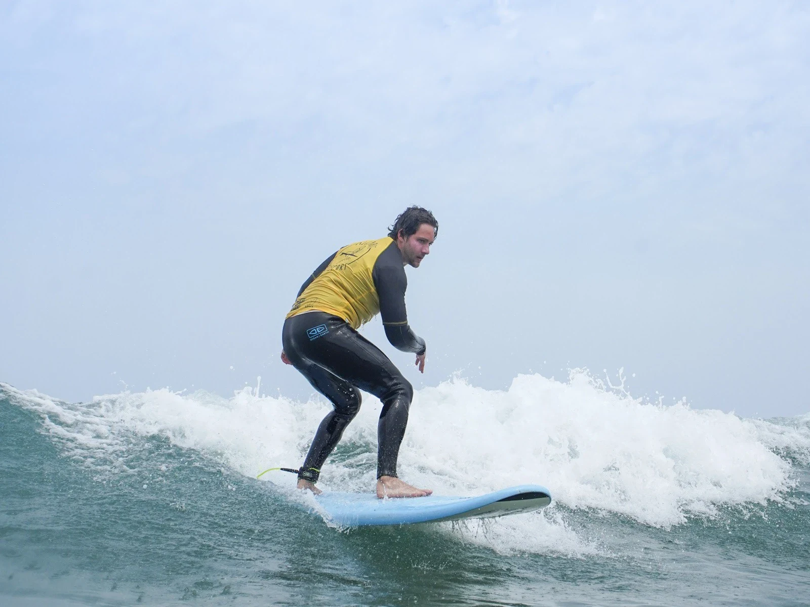 Man surfing a green wave in yellow lycra closeup