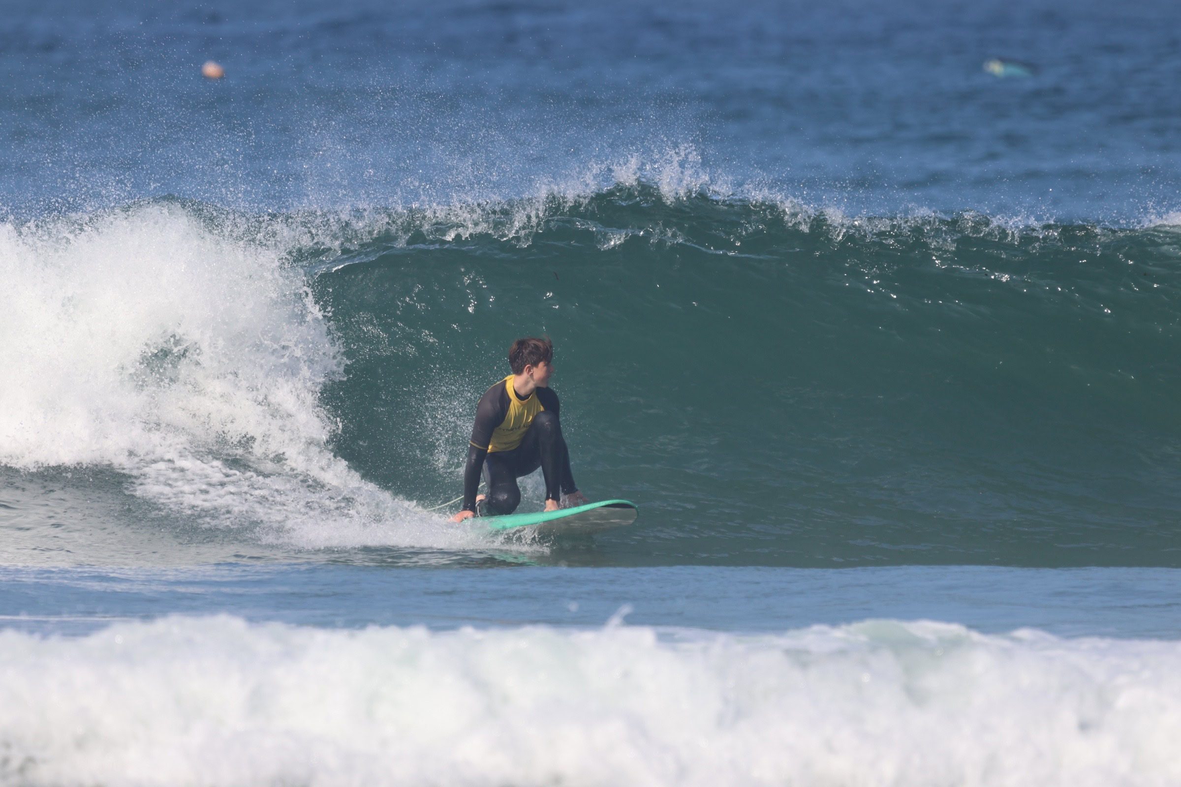 Surf student bottom turning on green wave during intermediate lesson, Algarve