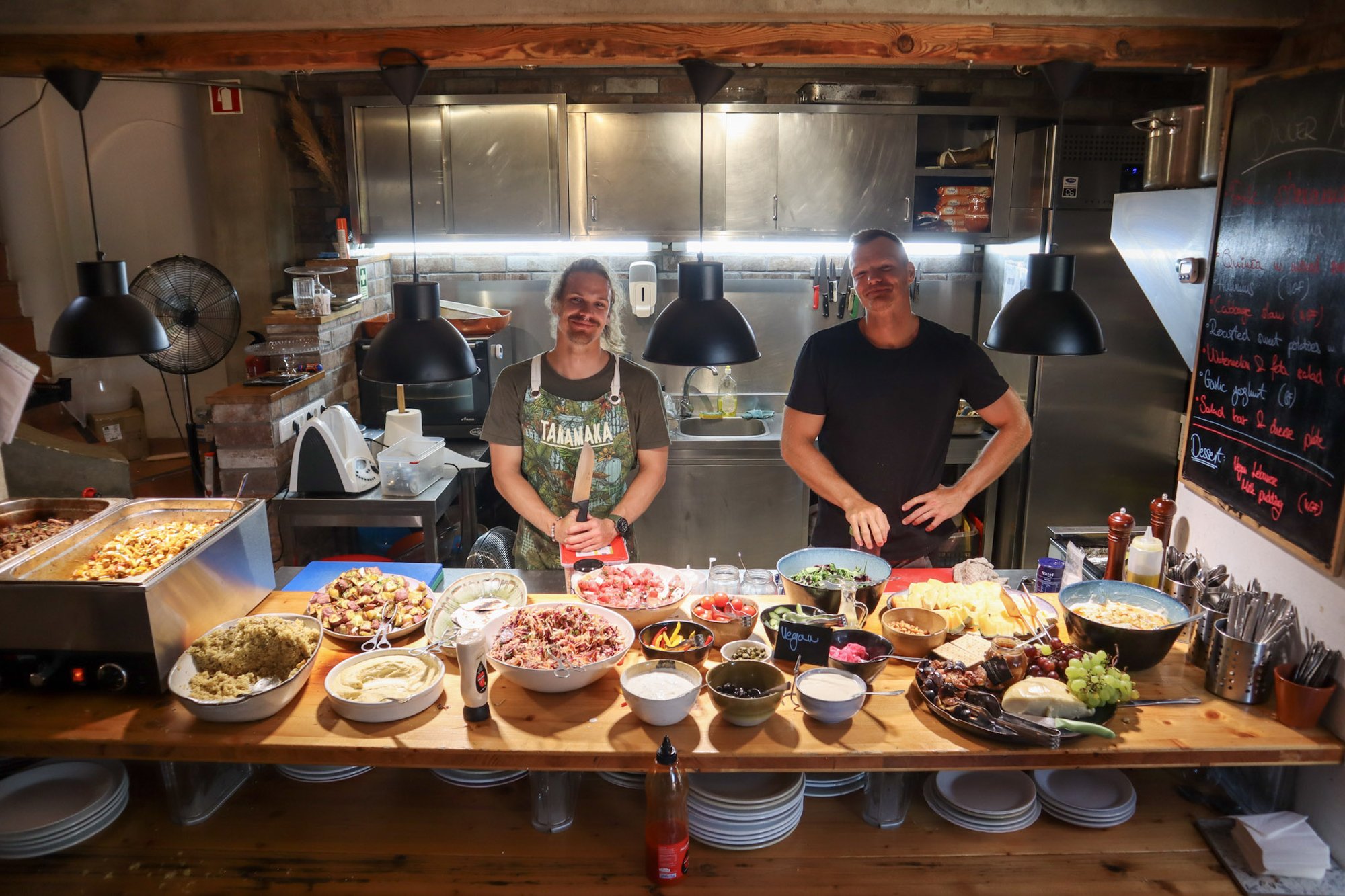 Two chefs standing behind full dinner buffet counter with salads and dips at Algarve Watersport surf camp