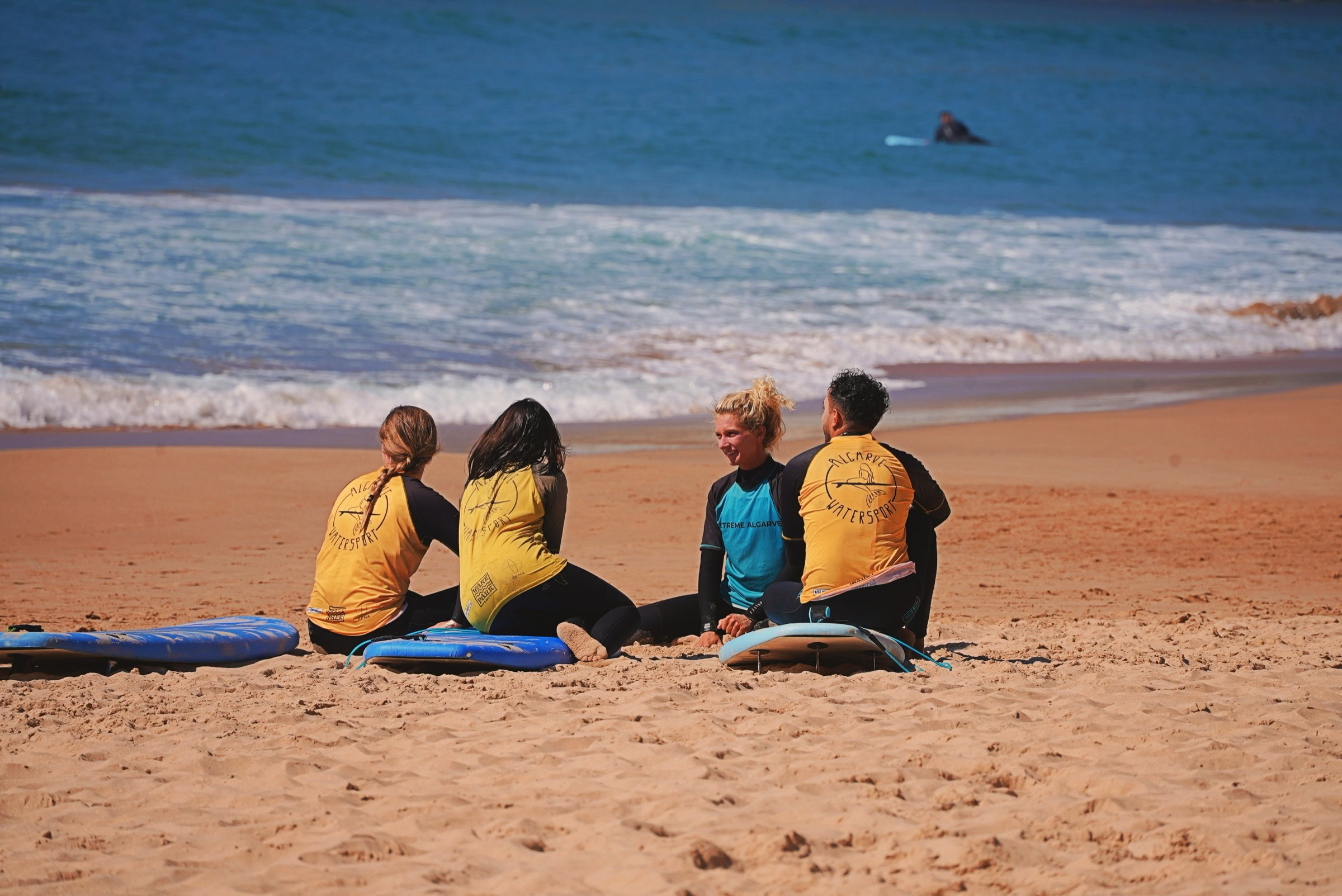 Surf friends sitting on the beach with boards, relaxing by the ocean — Algarve