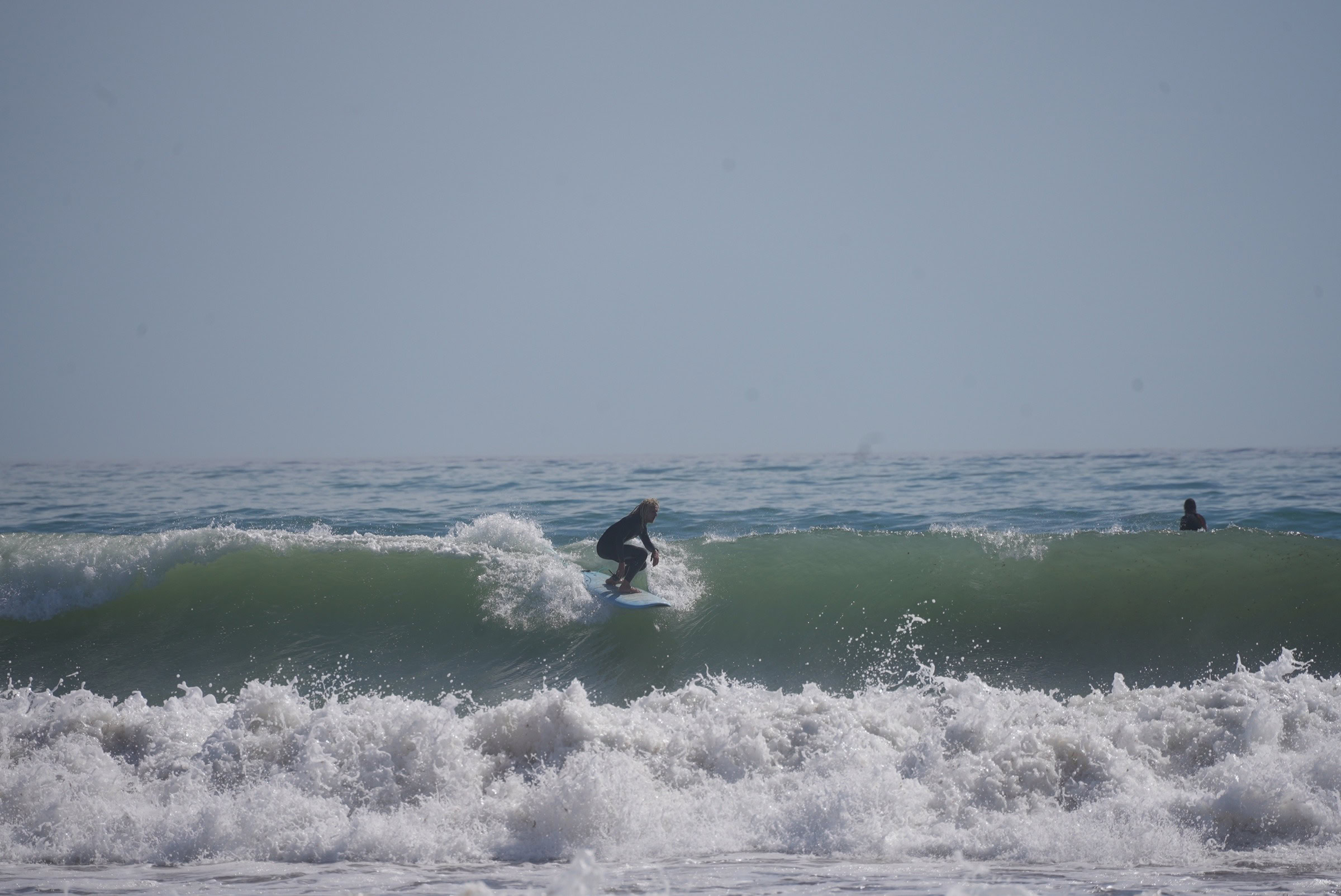 Surfer dropping into a big wave on the Algarve coast — this is what you're flying for
