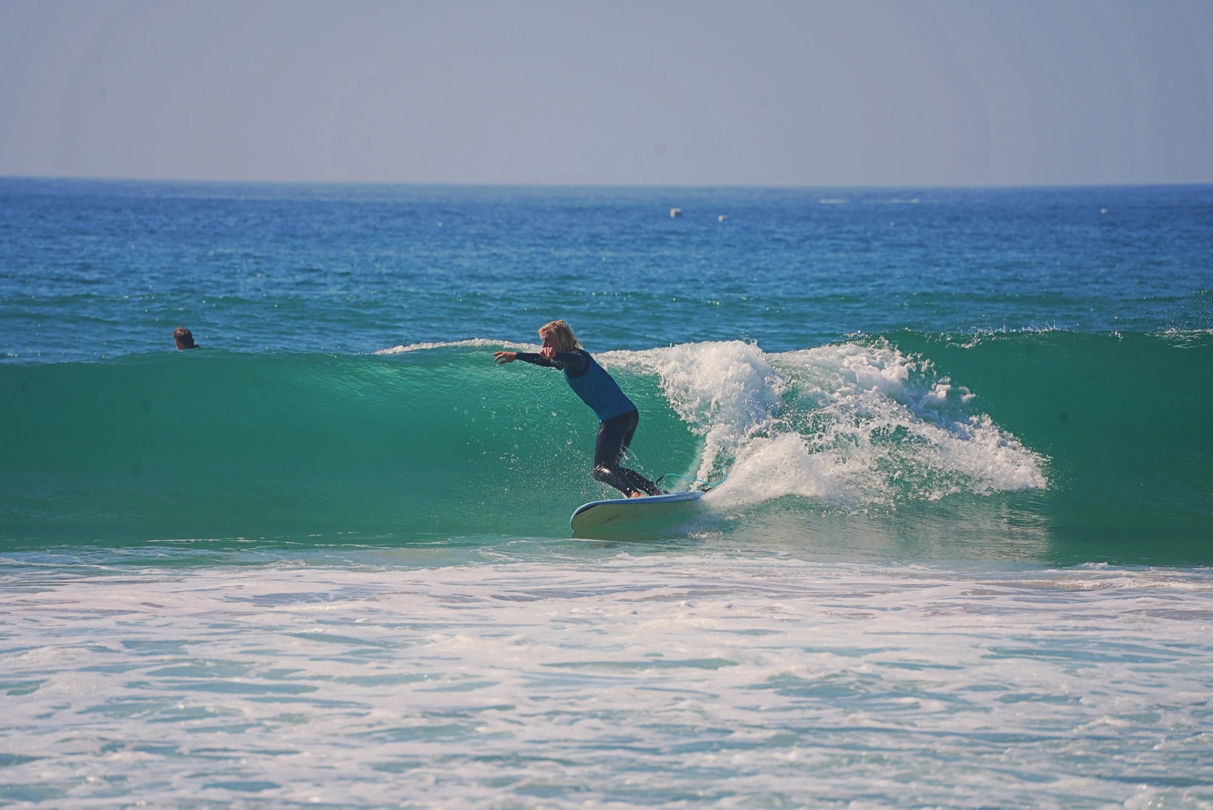 Surfer riding a clean green wave on a foam board in Portugal