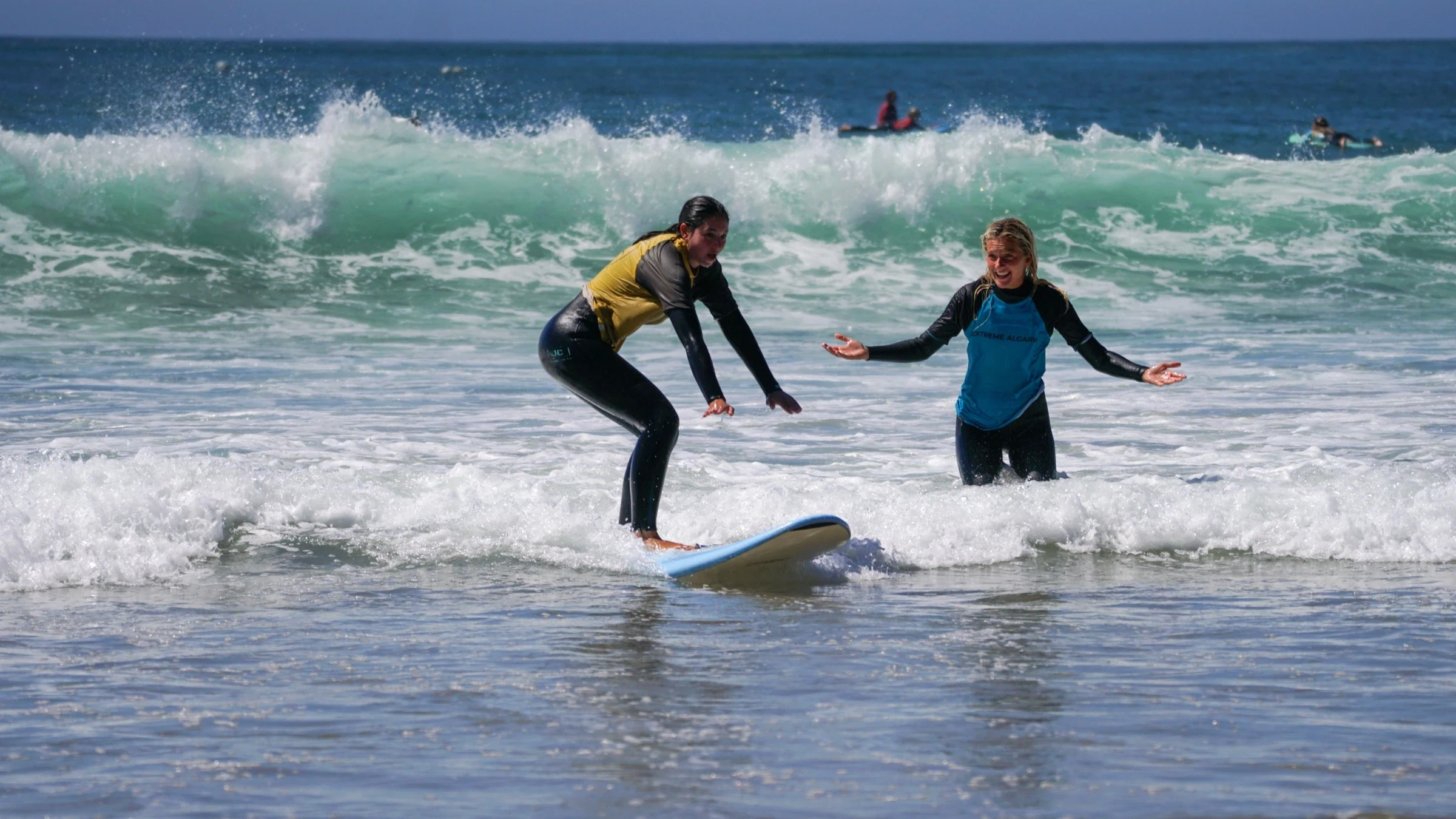 Two surf students riding white water waves together in Portugal