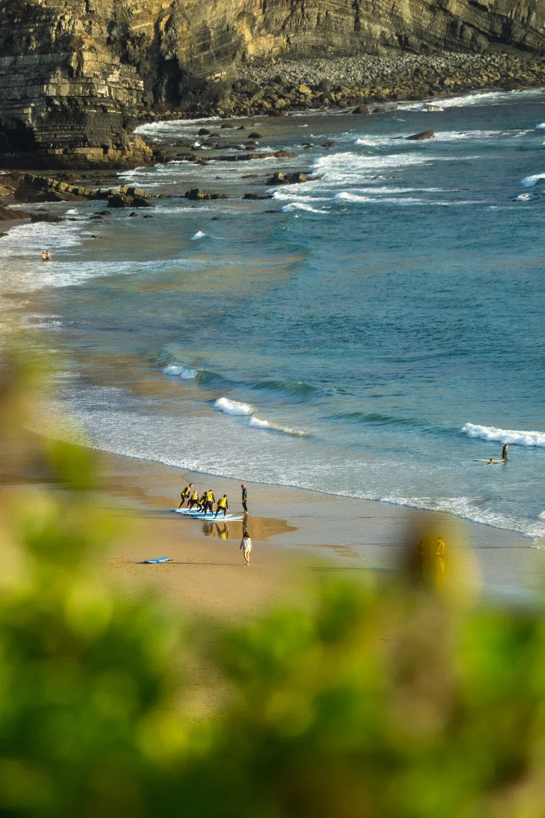 Vista elevata di una lezione di surf a Porto de Mós con le scogliere dell'Algarve
