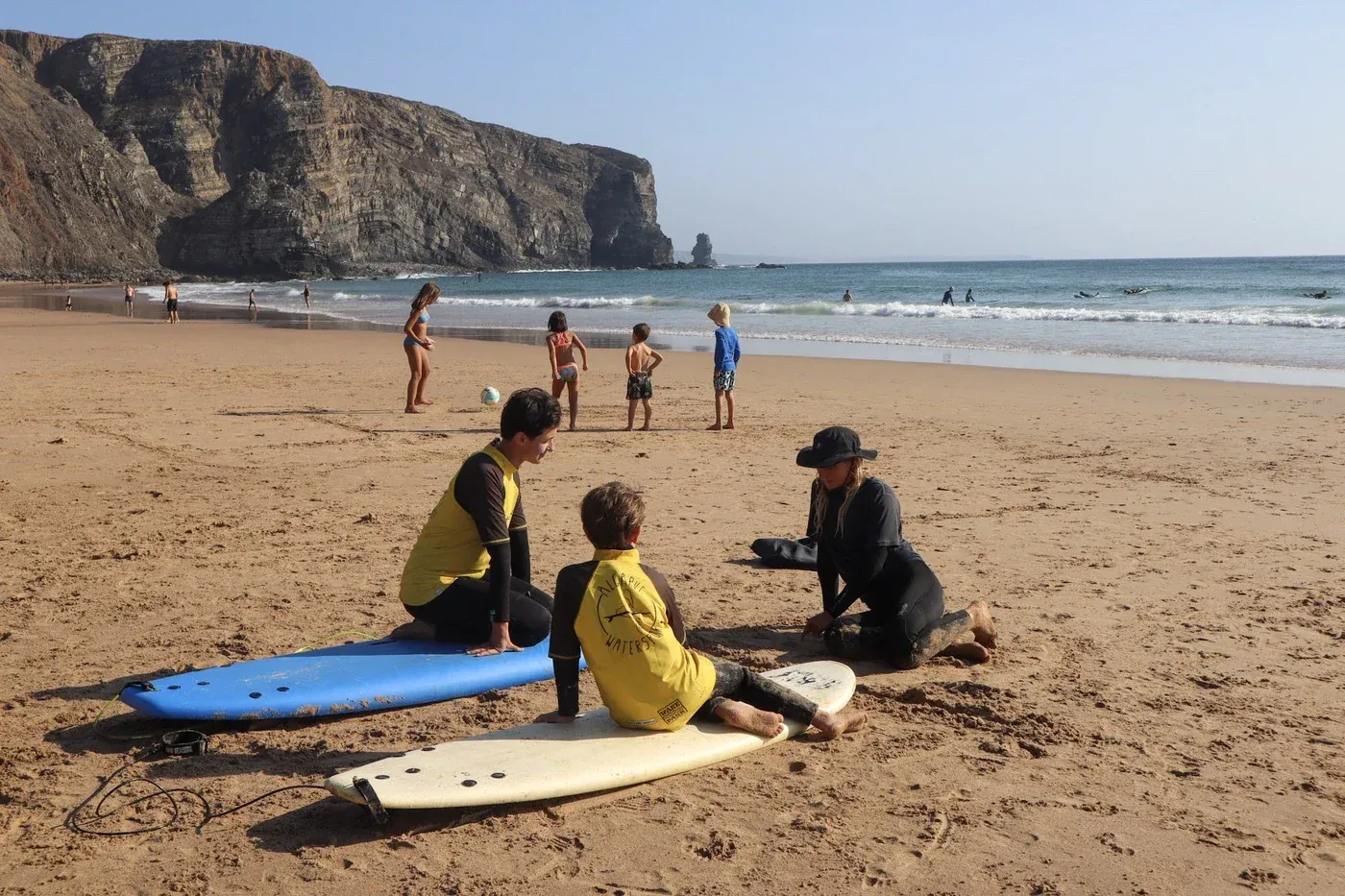 Istruttore che insegna surf ai bambini sulla spiaggia dell'Algarve con le scogliere