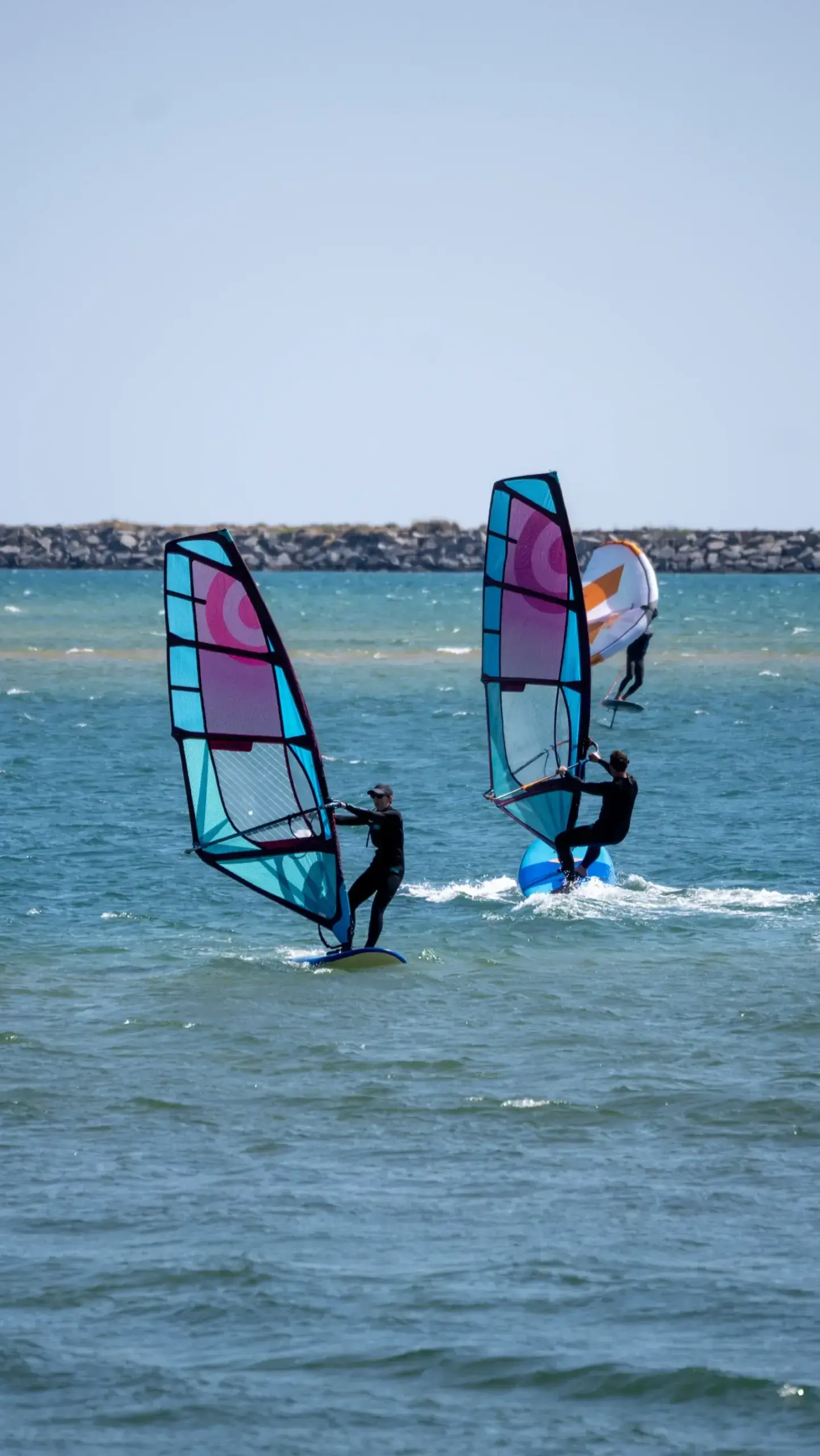 Zwei Windsurfer mit bunten Segeln an der Alvor-Lagune, Algarve