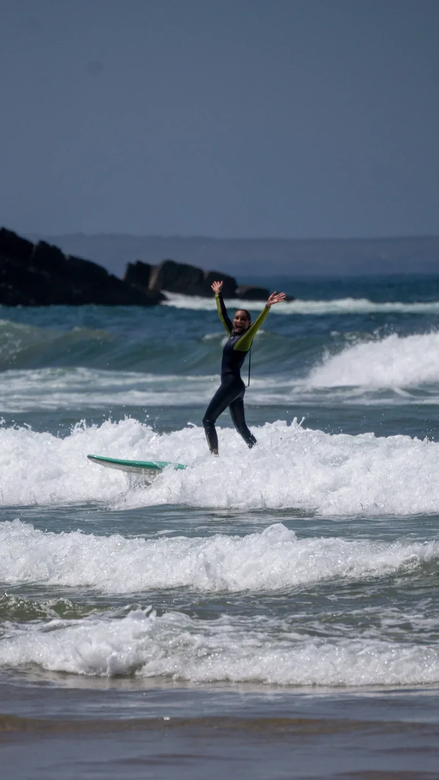 Surfista solitaria che festeggia dopo aver preso un'onda al surf camp in Algarve