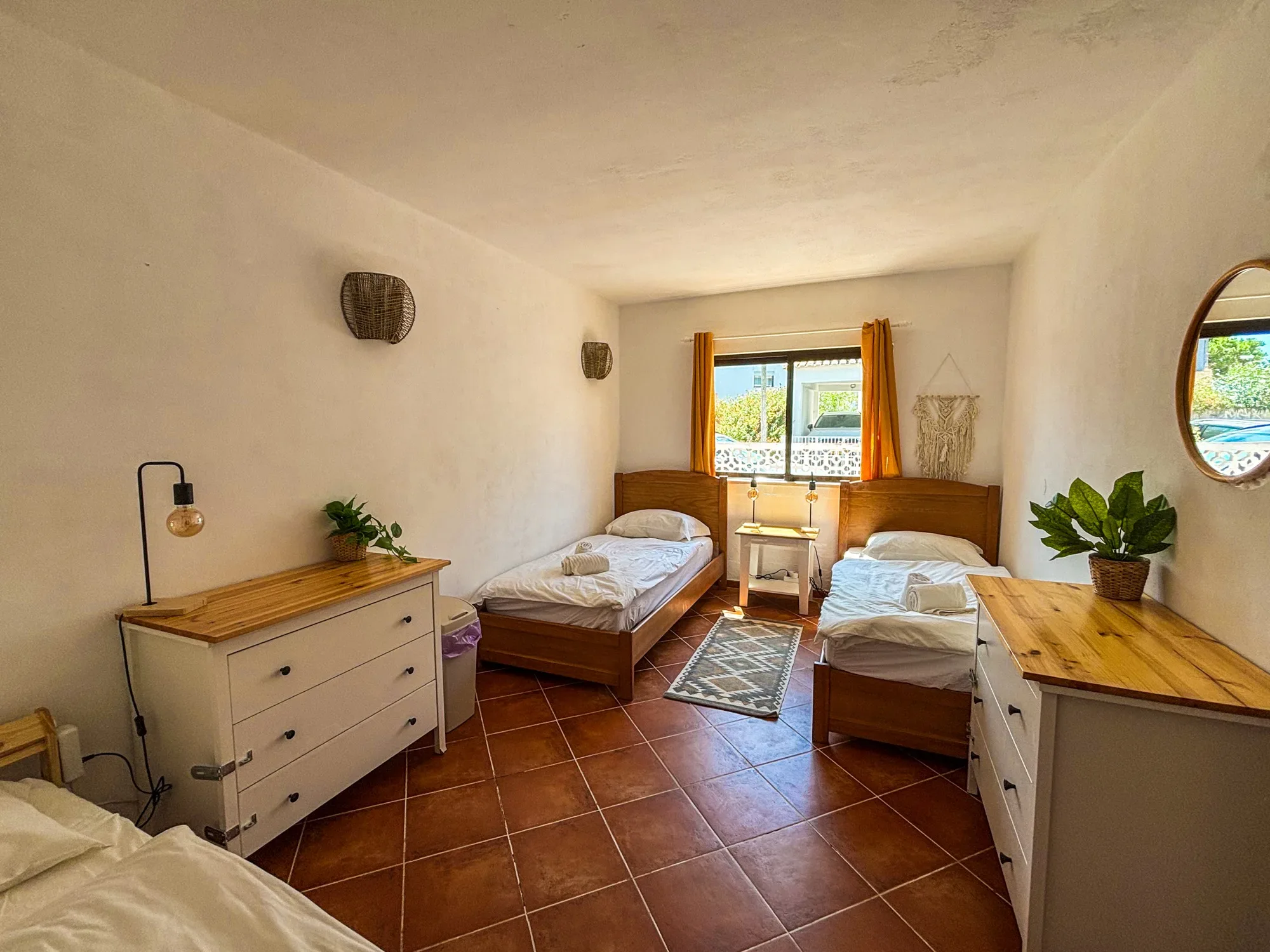 Triple room with three single beds, chests of drawers and mirror at Casa Alegria Lagos
