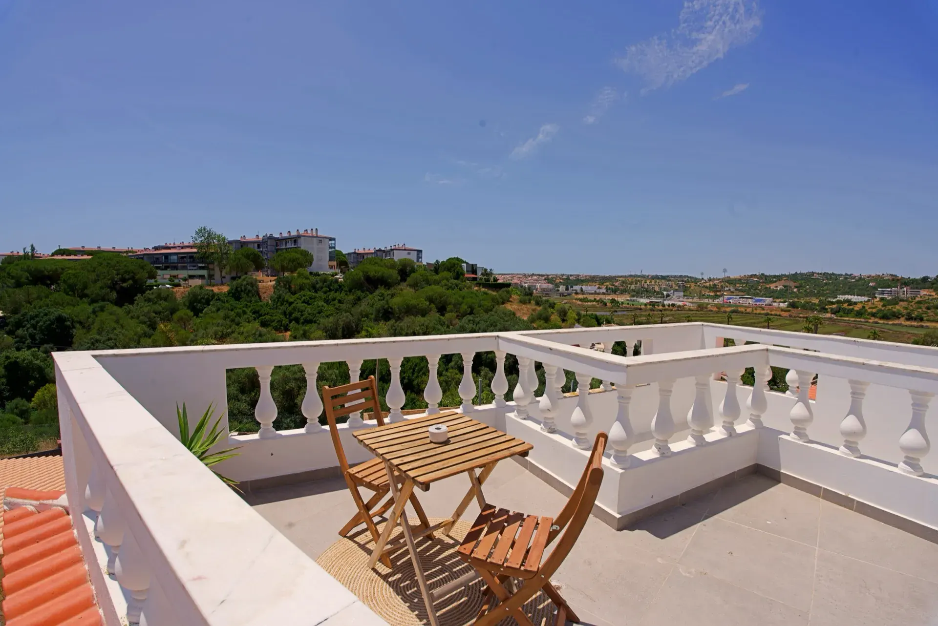 Rooftop terrace with a table and a view over green hills at The Hill, Lagos